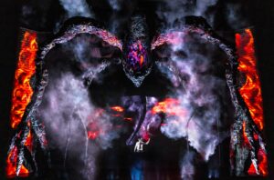 A giant Stranger Things monster standing over Henry on stage