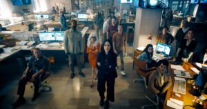 The entire staff of the Daily Planet stands in the newsroom, looking up toward the camera, in James Gunn’s Superman